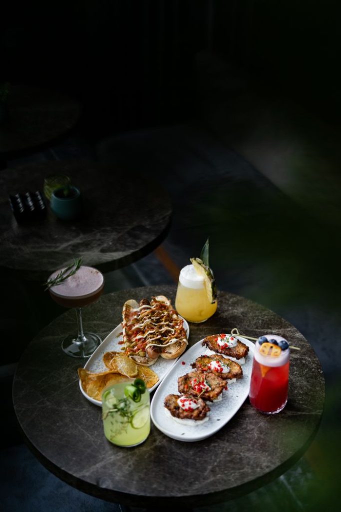 Stylish table setting featuring various cocktails and delicious appetizers on a dark marble surface.